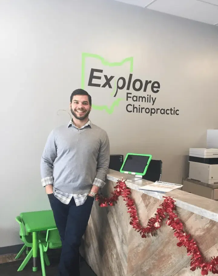 Chiropractor standing in front of the reception desk at Explore Family Chiropractic clinic.